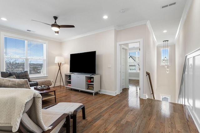 living room featuring a wealth of natural light, visible vents, crown molding, and wood finished floors