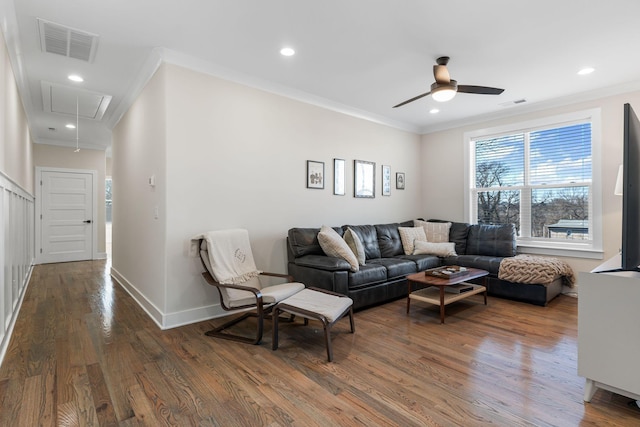 living area featuring visible vents, ornamental molding, wood finished floors, and attic access