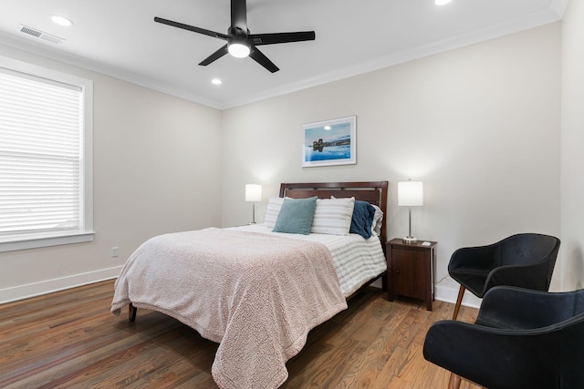 bedroom featuring ornamental molding, visible vents, baseboards, and wood finished floors