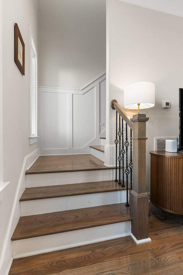 staircase featuring radiator, wainscoting, a decorative wall, and wood finished floors