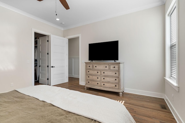 bedroom featuring visible vents, baseboards, dark wood-style flooring, a walk in closet, and crown molding