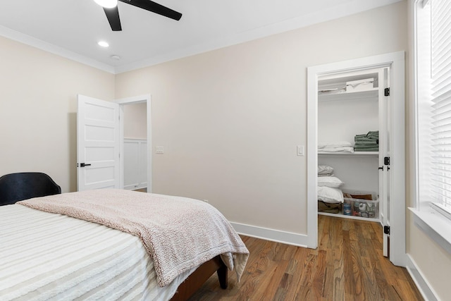 bedroom featuring crown molding, a closet, a spacious closet, wood finished floors, and baseboards