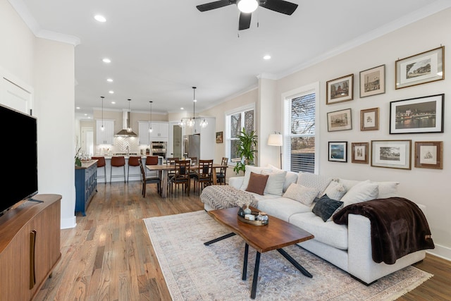 living room with crown molding, light hardwood / wood-style floors, and ceiling fan