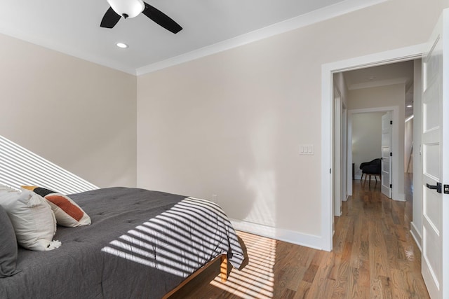 bedroom with ceiling fan, crown molding, baseboards, and wood finished floors