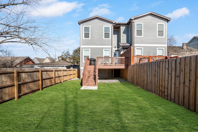 rear view of house featuring a fenced backyard, stairway, a lawn, and a wooden deck