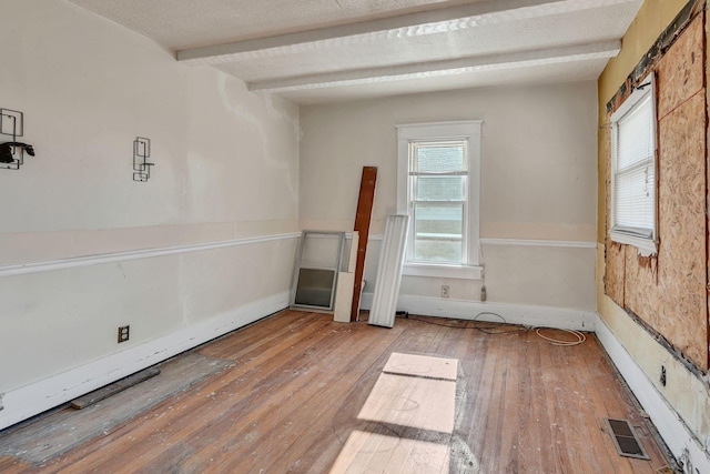 spare room with hardwood / wood-style flooring and beam ceiling