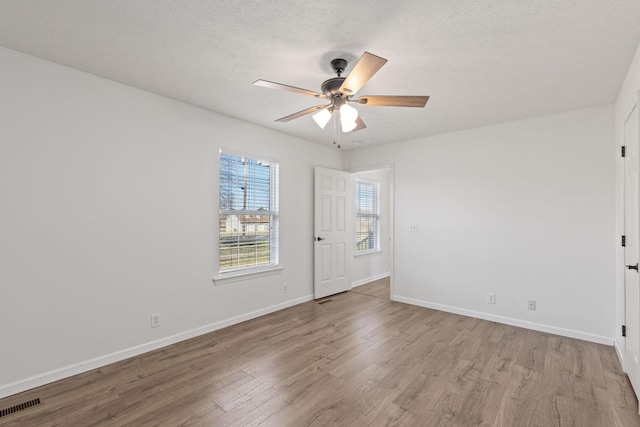 spare room with ceiling fan, a textured ceiling, and light hardwood / wood-style floors