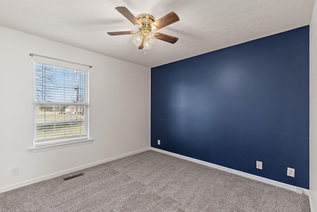 empty room with ceiling fan, a textured ceiling, and carpet