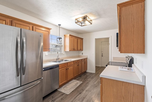 kitchen featuring sink, hanging light fixtures, a textured ceiling, appliances with stainless steel finishes, and dark hardwood / wood-style flooring