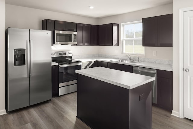 kitchen with a kitchen island, sink, hardwood / wood-style flooring, stainless steel appliances, and dark brown cabinets