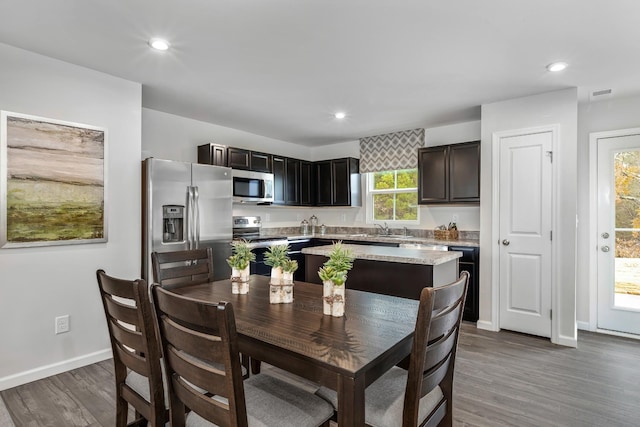 kitchen with appliances with stainless steel finishes, dark hardwood / wood-style floors, a center island, and sink