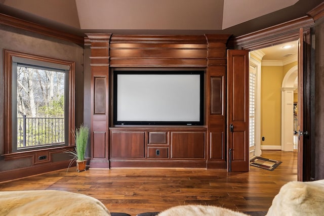 home theater room with dark wood-type flooring and ornamental molding