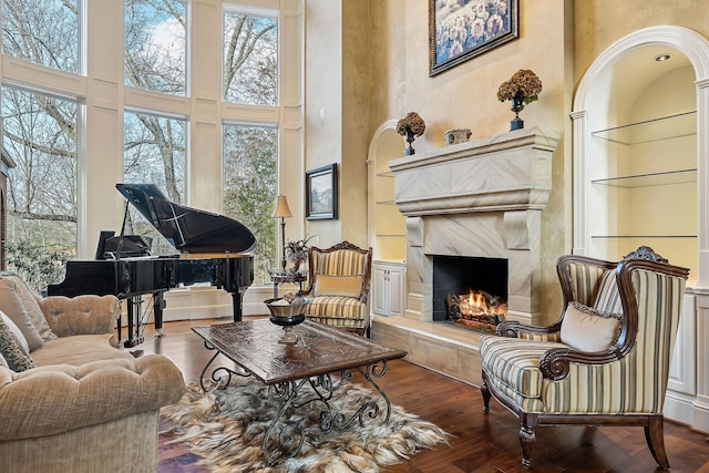 sitting room featuring a towering ceiling, wood-type flooring, and a premium fireplace