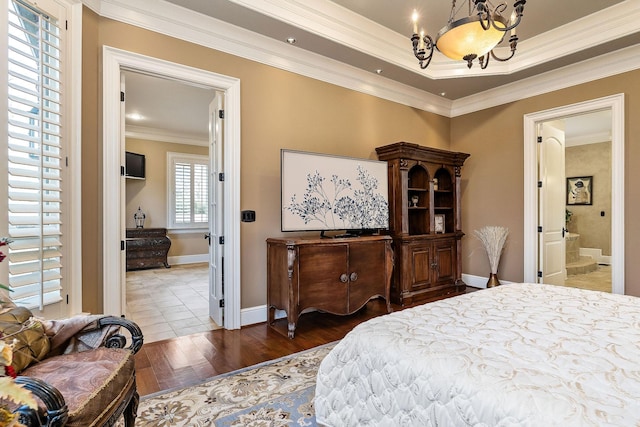 bedroom featuring hardwood / wood-style flooring, ensuite bath, crown molding, and a notable chandelier