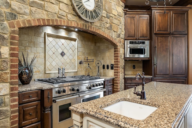 kitchen featuring light stone counters, sink, tasteful backsplash, and stainless steel appliances