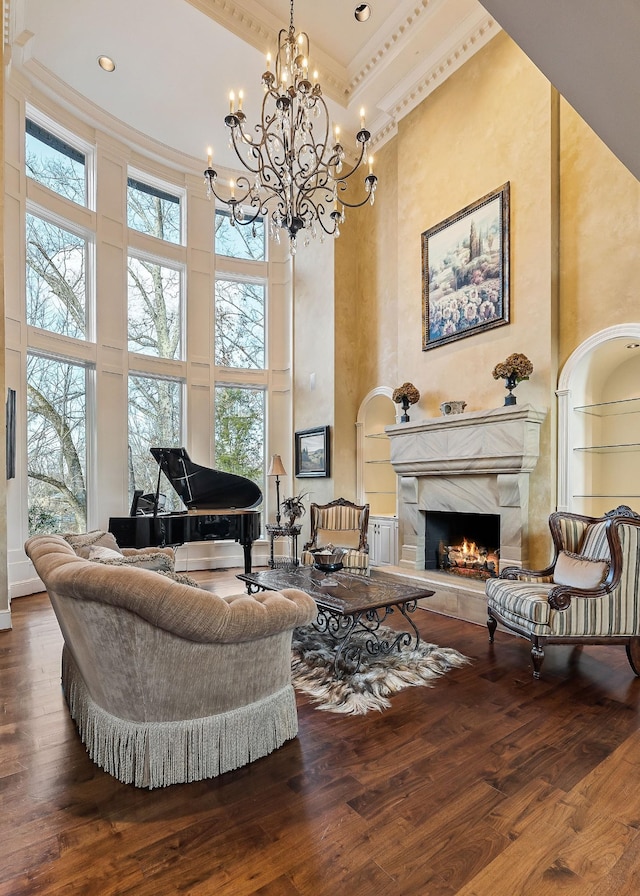 living area featuring a towering ceiling, a fireplace, ornamental molding, and wood-type flooring