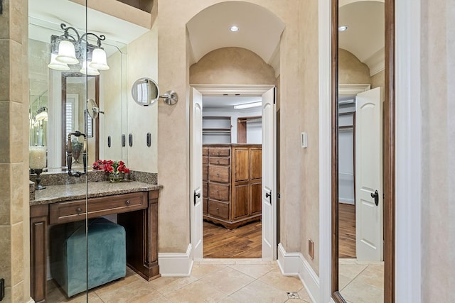 bathroom featuring vaulted ceiling, vanity, a chandelier, and tile patterned flooring