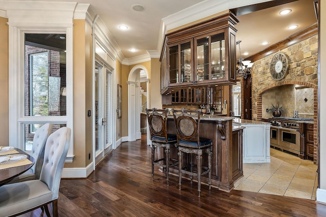 bar with double oven range, decorative light fixtures, stone countertops, and light wood-type flooring