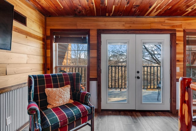 doorway with dark wood-type flooring, french doors, and wood walls