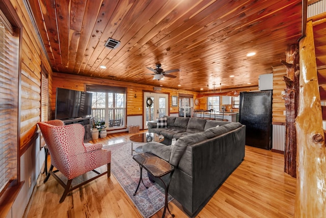 living room featuring wood ceiling, ceiling fan, rustic walls, and light wood-type flooring