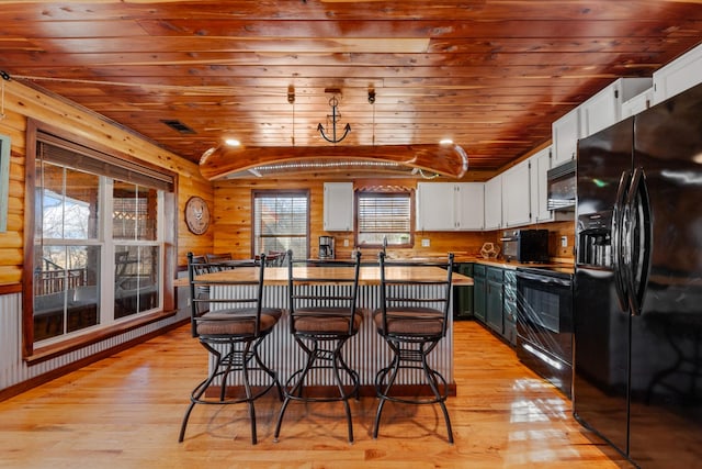 kitchen with white cabinets, black appliances, wooden ceiling, and a kitchen bar