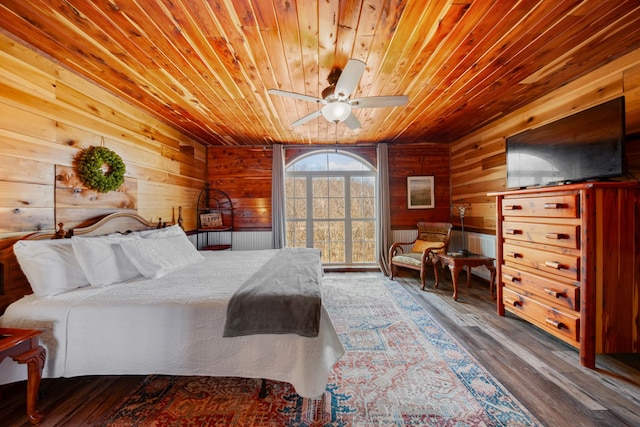 bedroom with wood ceiling, ceiling fan, wood-type flooring, and wooden walls