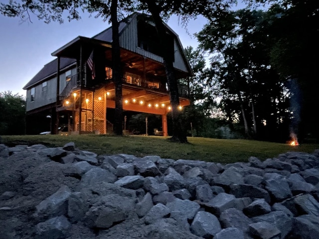 back house at dusk with a balcony and a yard