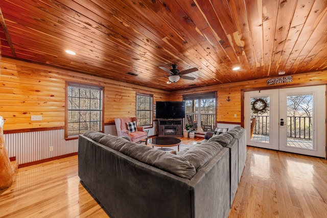 living room featuring log walls, french doors, ceiling fan, and light wood-type flooring