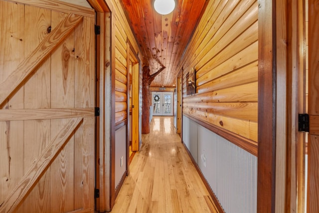 hall with wood ceiling, light hardwood / wood-style floors, and rustic walls