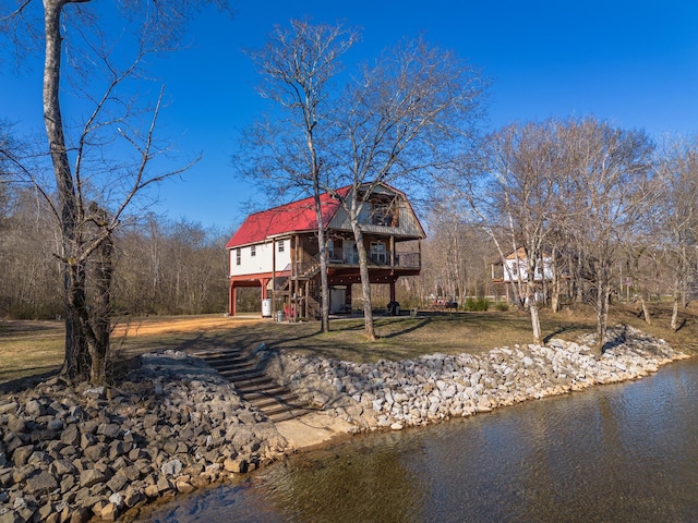 rear view of house featuring a water view and a lawn