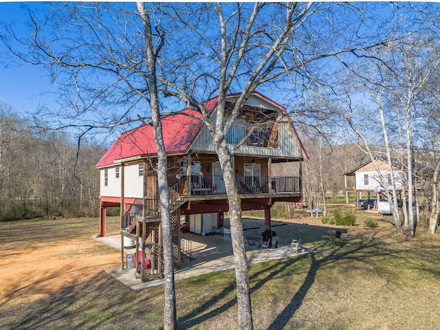 view of front of property featuring a wooden deck, a front lawn, and a patio area