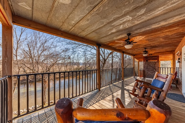 wooden deck with ceiling fan and a water view