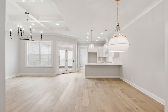 kitchen with ornamental molding, coffered ceiling, pendant lighting, and light hardwood / wood-style flooring