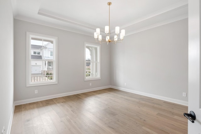 empty room featuring an inviting chandelier, crown molding, a raised ceiling, and light wood-type flooring