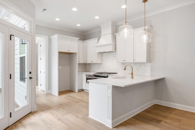 kitchen with custom range hood, pendant lighting, white cabinets, and decorative backsplash