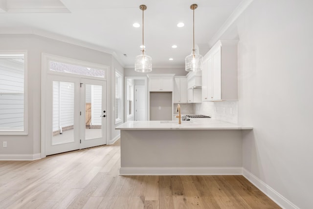 kitchen featuring pendant lighting, sink, white cabinetry, and crown molding