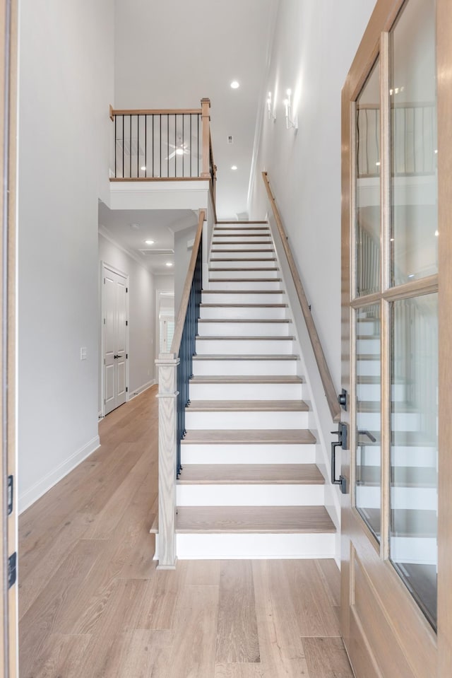 staircase with hardwood / wood-style floors and crown molding