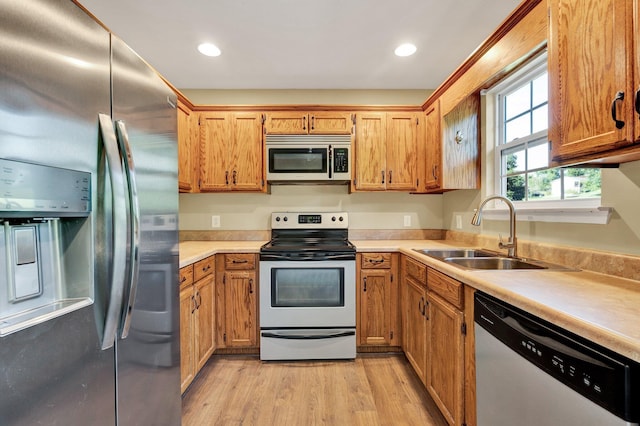 kitchen featuring appliances with stainless steel finishes, light countertops, light wood-style floors, a sink, and recessed lighting