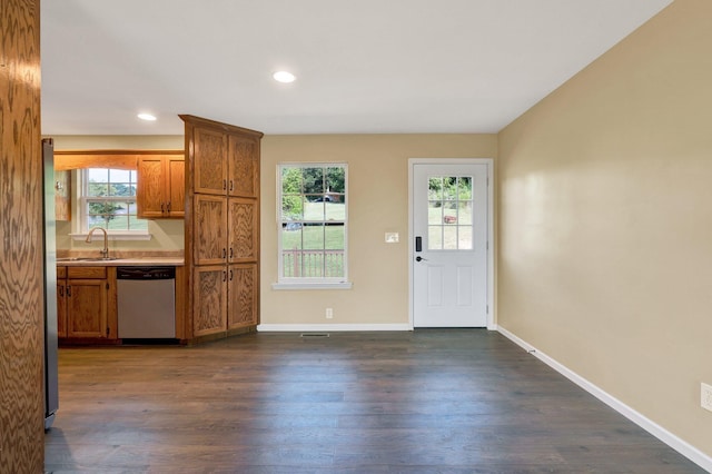 kitchen with brown cabinets, dark wood-type flooring, stainless steel appliances, and light countertops