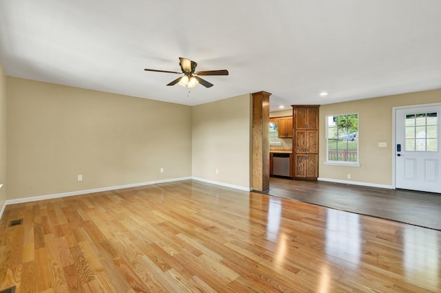 unfurnished living room with ceiling fan, light wood-style flooring, visible vents, and baseboards