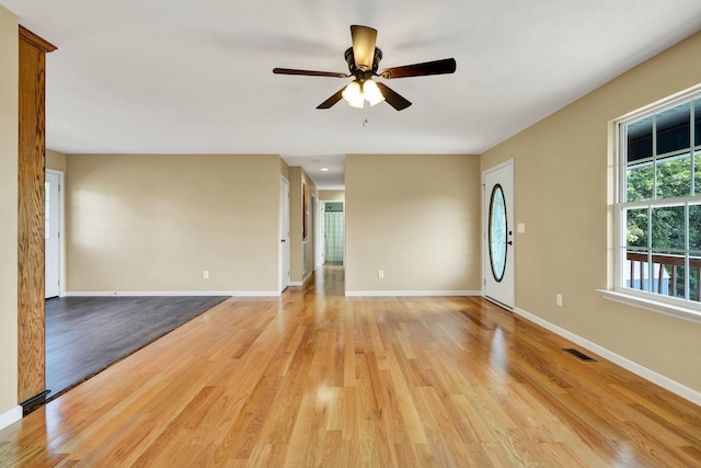 unfurnished room with light wood-style floors, visible vents, baseboards, and a ceiling fan