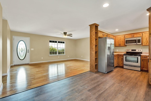 kitchen with light countertops, appliances with stainless steel finishes, brown cabinetry, open floor plan, and wood finished floors