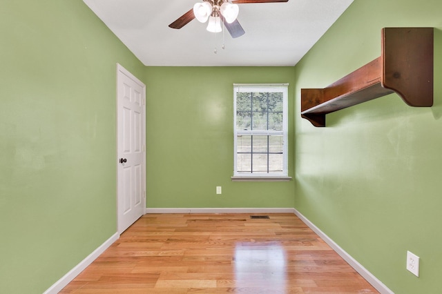 spare room featuring a ceiling fan, light wood-style flooring, and baseboards