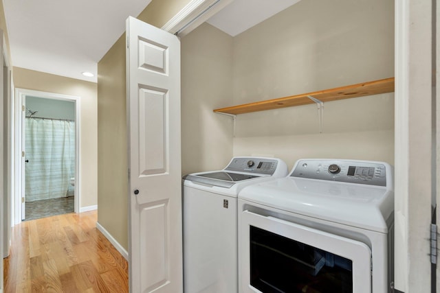 washroom featuring light wood-type flooring, laundry area, washer and clothes dryer, and baseboards