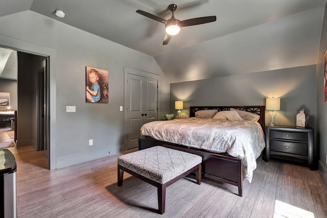 bedroom with vaulted ceiling, a closet, ceiling fan, and light wood-type flooring