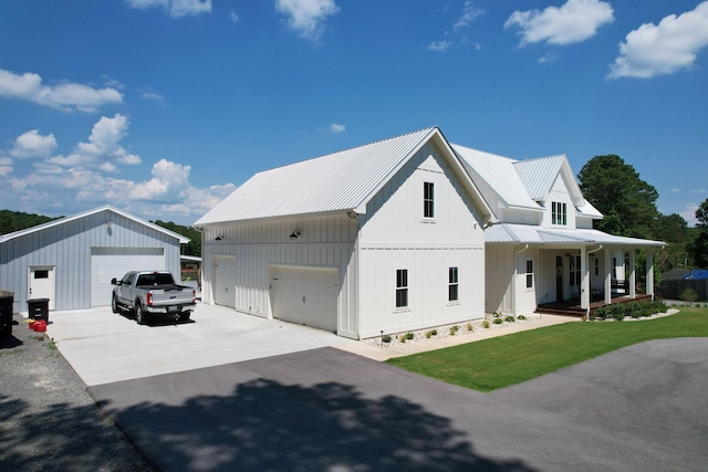 modern farmhouse style home with an outbuilding, a garage, a front lawn, and a porch