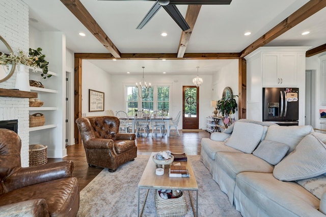 living room with a notable chandelier, a brick fireplace, built in features, and light wood-type flooring