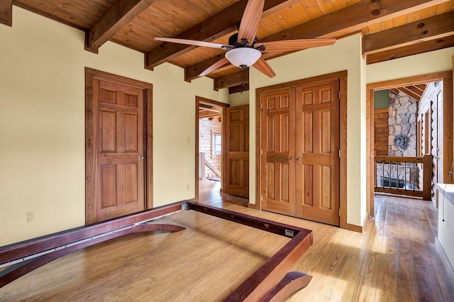 unfurnished bedroom with beamed ceiling, wood ceiling, and light wood-type flooring