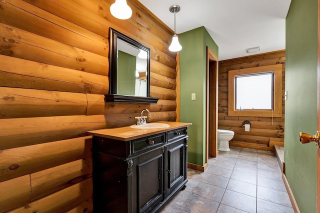 bathroom featuring vanity, log walls, tile patterned floors, and toilet