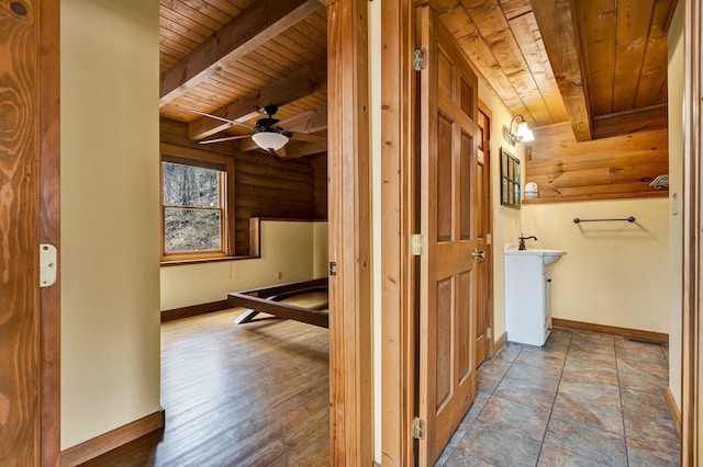 corridor with beamed ceiling, rustic walls, and wood ceiling